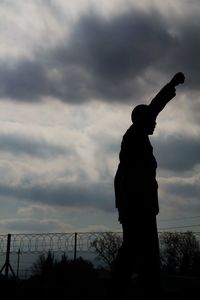 Low angle view of silhouette man standing by railing against sky