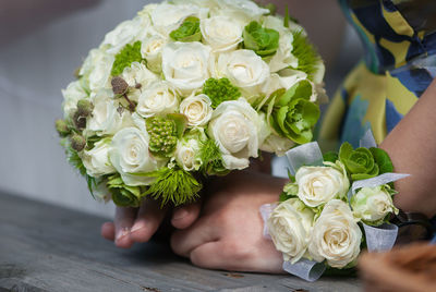 Cropped image of bride holding bouquet while wearing corsage