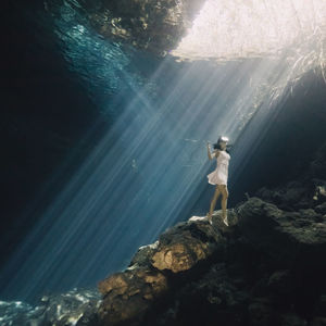 Man standing on rock by sea