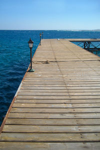 Pier over sea against clear blue sky