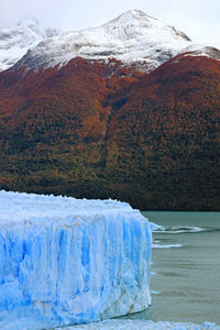 Scenic view of iceberg against snowcapped mountain