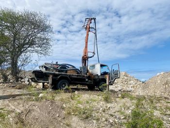 Low angle view of abandoned vehicle on field against sky