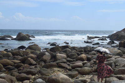 Scenic view of rocks by sea against sky