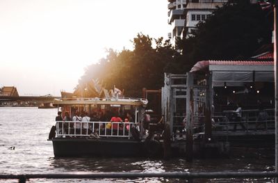 Boats in river by buildings against sky
