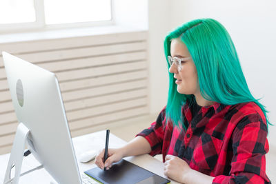 Young woman using mobile phone while sitting on table