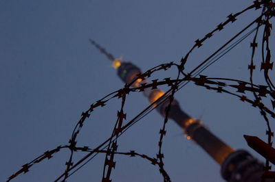 Low angle view of razor wire and ostankino tower against sky at dusk