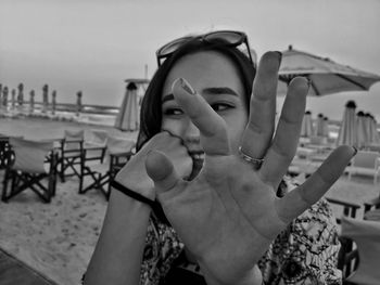 Close-up of woman showing stop gesture while sitting at beach restaurant