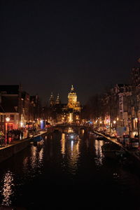 Illuminated buildings by river at night