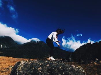 Woman standing on mountain against blue sky