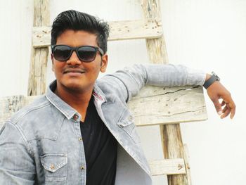 Young man wearing sunglasses leaning on ladder