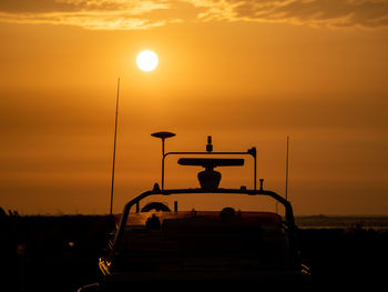 Silhouette car on street against orange sky