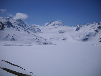 Scenic view of snow covered mountains against blue sky