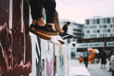 Low section of people sitting on graffiti wall