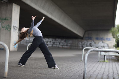 Young woman dancing under bridge