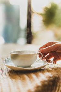 Hand holding tea cup on table