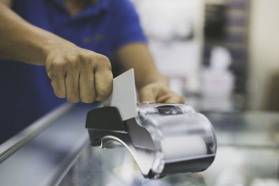 Midsection of man making credit card payment by machinery