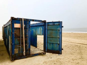 Metal container at beach against clear sky
