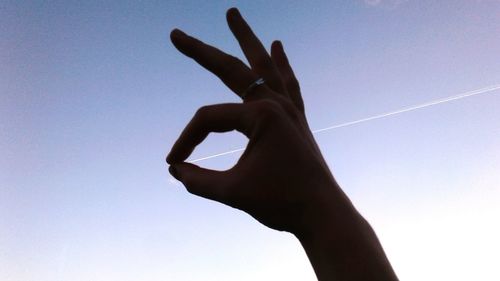 Low angle view of silhouette hand against clear sky