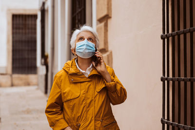 Young woman drinking water while standing in city