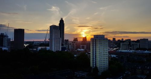 Modern buildings in city against sky during sunset