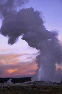 Smoke emitting from volcanic landscape against sky during sunset