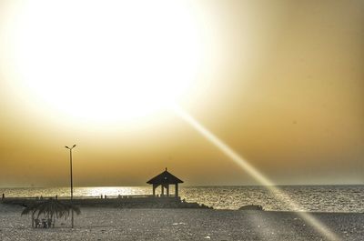 Silhouette people on beach against clear sky during sunset