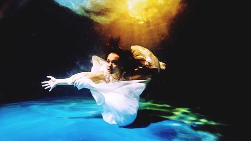 Man swimming in water against black background