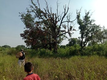 People on field by trees against sky