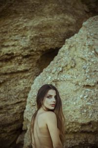 Portrait of woman on rock against wall