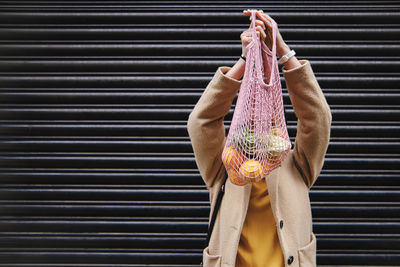 Woman holding mesh bag near shutter