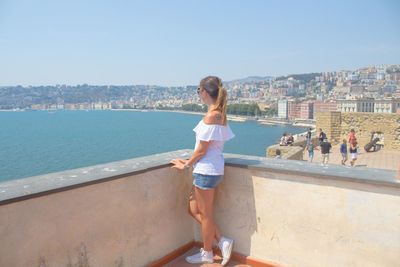 Full length of woman looking at view while standing against sky