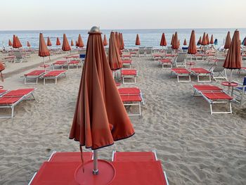 Empty chairs and lounge chair at beach against sky