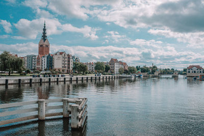 Bridge over river by buildings in city against sky