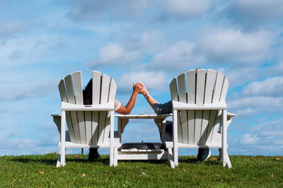 Woman sitting on chair against sky