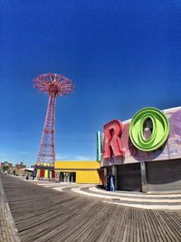 Low angle view of ferris wheel against clear blue sky