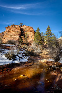 Stream flowing through rocks against sky