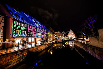 Illuminated bridge over canal in city at night