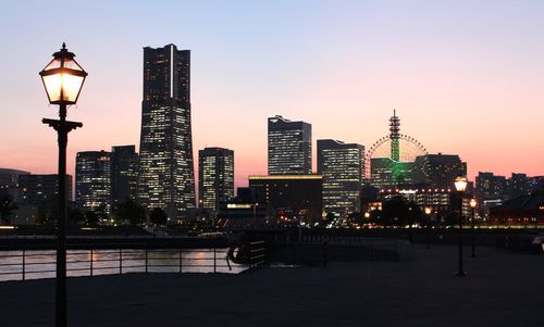 Illuminated city scape against sky at dusk