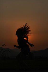 Side view of silhouette woman against orange sky