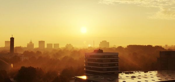 Buildings in city against sky during sunset