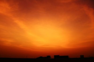Silhouette buildings against orange sky