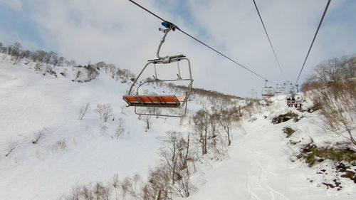 Ski lift over snow covered mountains against sky