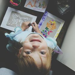 Directly above portrait of girl drawing on paper at home