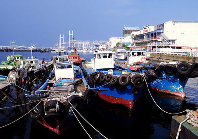 Boats moored at harbor against clear sky