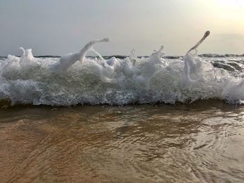 Waves splashing on shore against sky