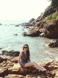 Woman sitting on rocks at beach