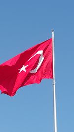 Low angle view of flag against clear blue sky