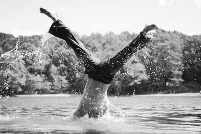 Shirtless man performing headstand in river