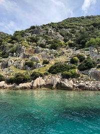 Scenic view of rocks by sea against sky