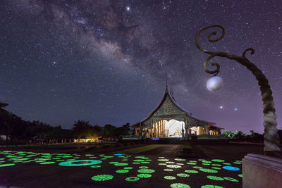 Low angle view of illuminated temple against star field at night